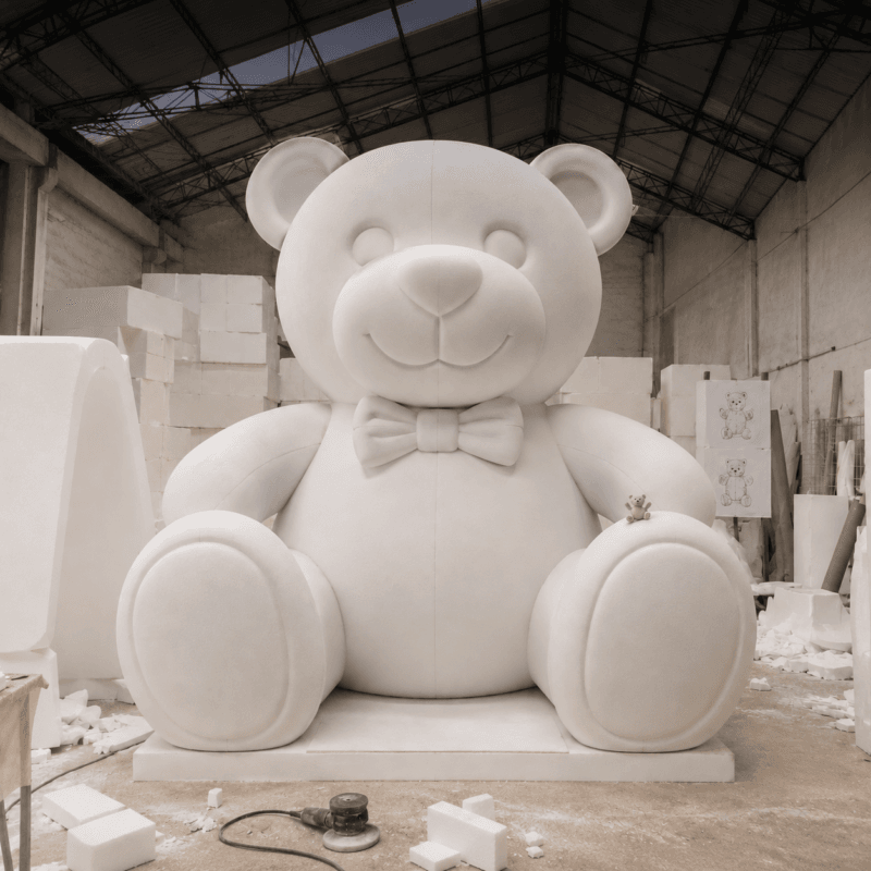 Unfinished white teddy bear sculpture with a bow tie