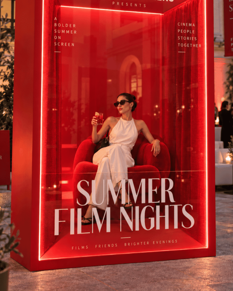 Guest seated inside a red illuminated SUMMER FILM NIGHTS photo installation